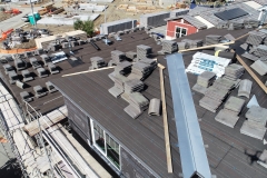 aerial view of under construction dwelling units showing rooftops with stacks of roof finish material ready for installation