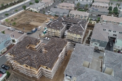 aerial view of multiple rooftops of a residential community at various stages of construction