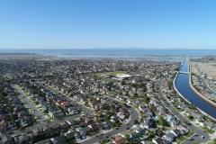 wide aerial view of residential neighborhood in foreground and body of water in distant background