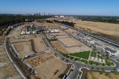 aerial view of development site with lots at various stages of construction and tall buildings can be seen in the background