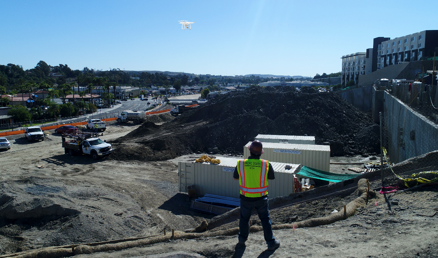 drone pilot flying drone over a stock pile at a construction site